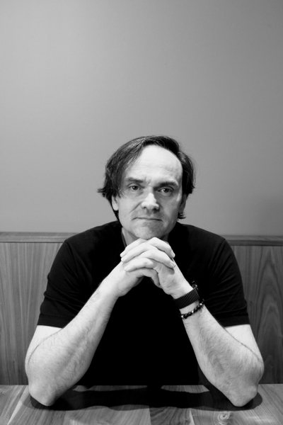 Torsten Schulz, seated at a table, hands folded under his chin.