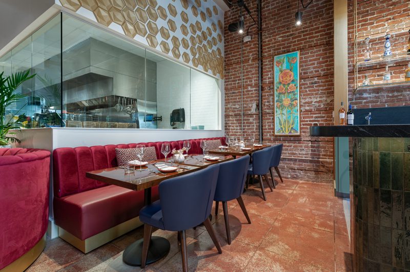 Red leather banquette and set tables in front of the open kitchen.
